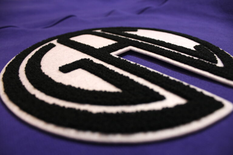 Black and white chenille monogram patch on a purple garment