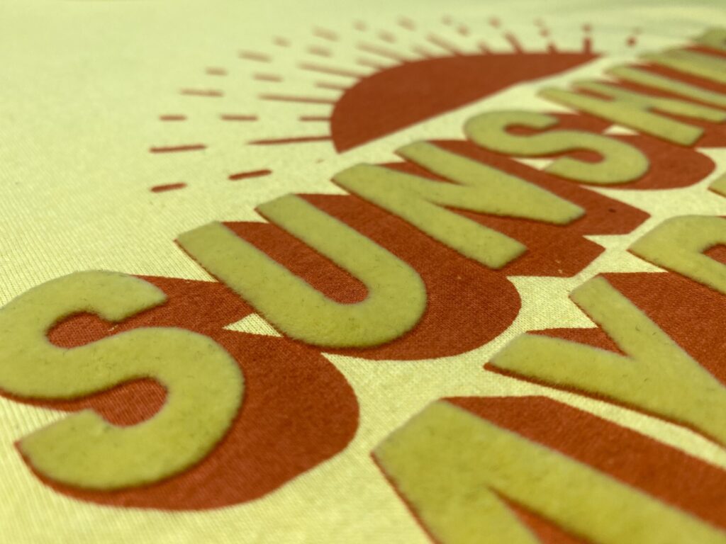 flocked sunshine lettering on a yellow t-shirt