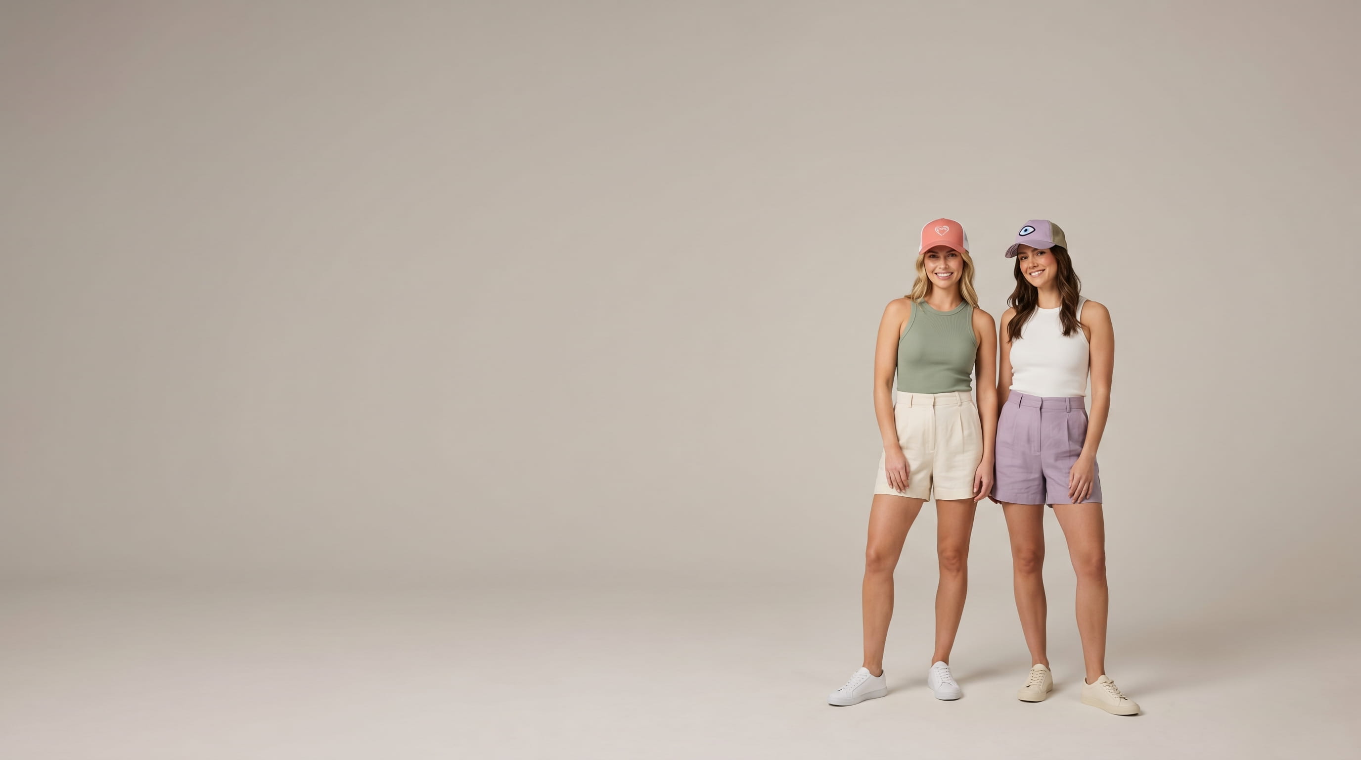 Two women modeling decorated Infinity Her women's lifestyle caps in a clean studio