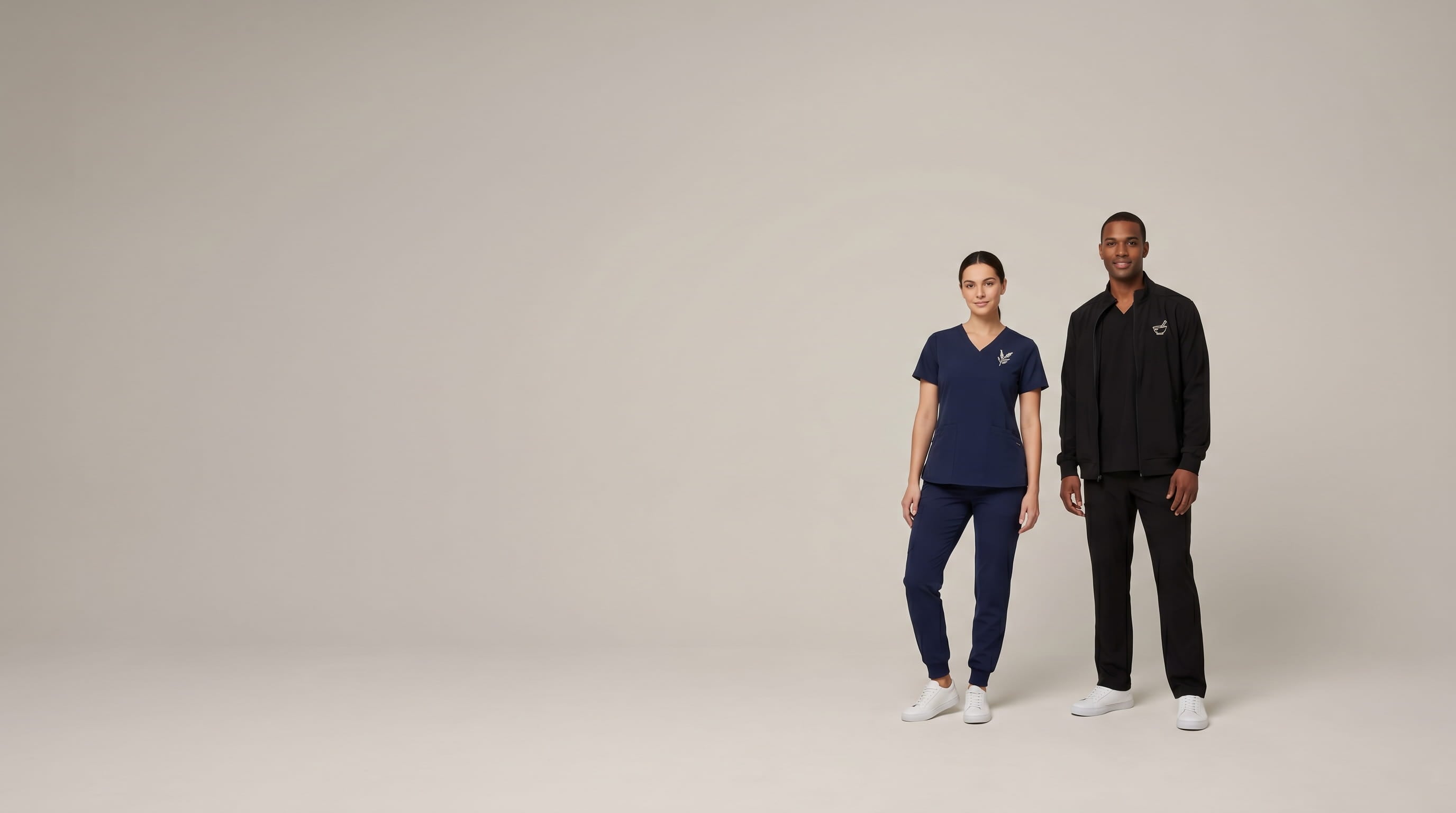 Two healthcare professionals modeling decorated Jaanuu medical scrubs in a clean studio