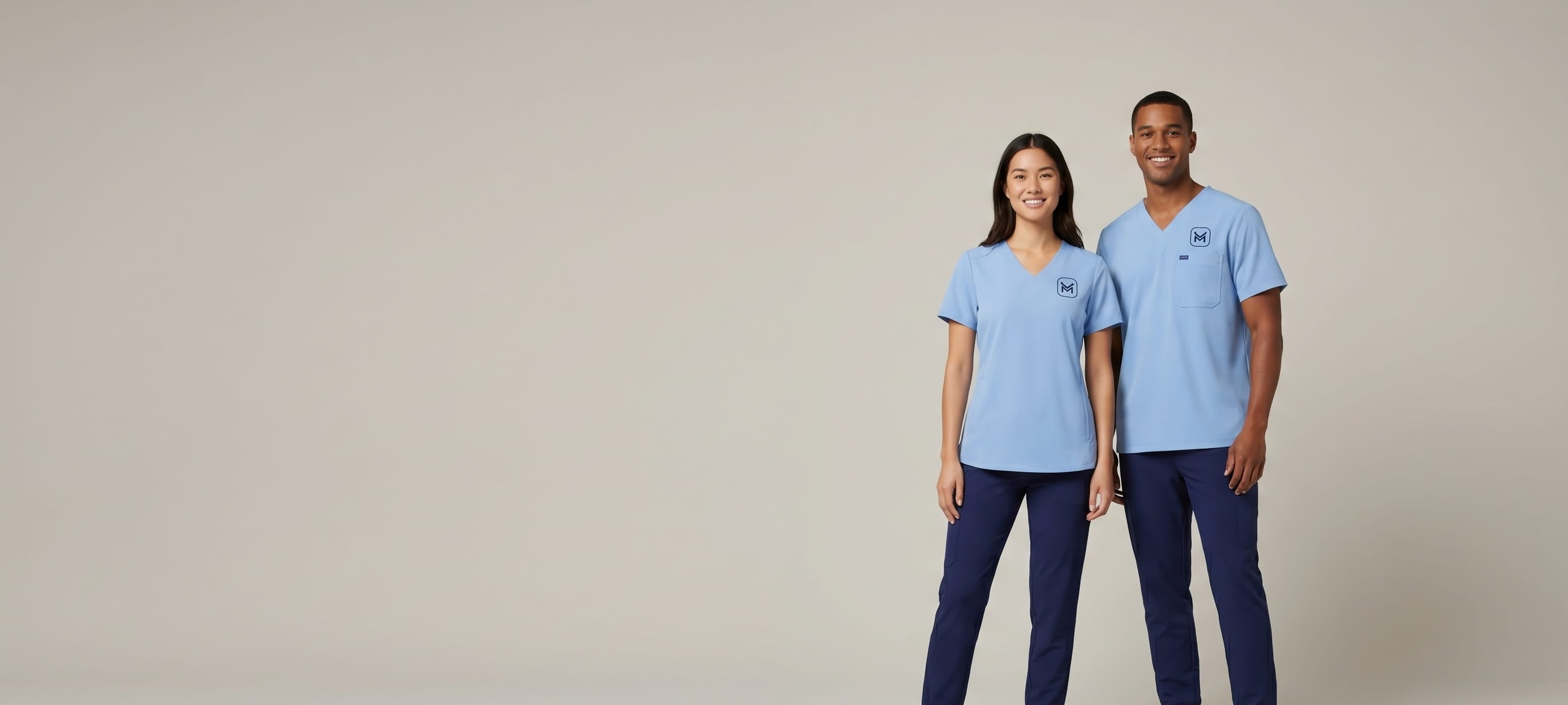 Female and male healthcare professionals wearing matching light blue and navy decorated Jaanuu custom scrub sets