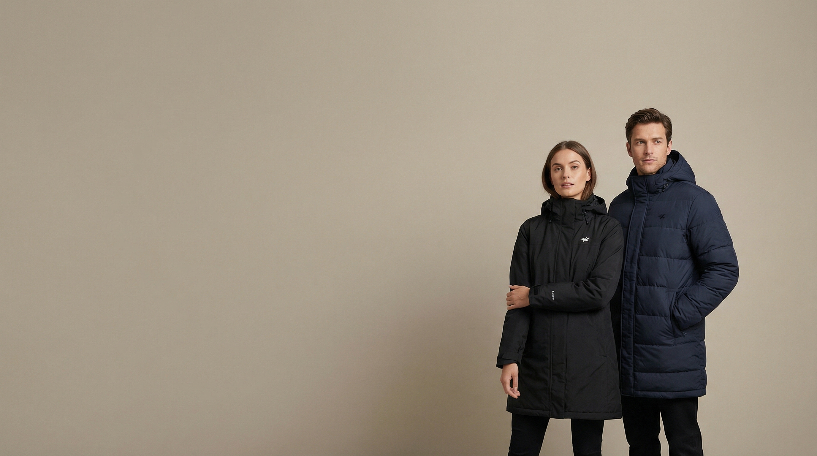 Man and woman wearing custom decorated parkas with embroidered logos