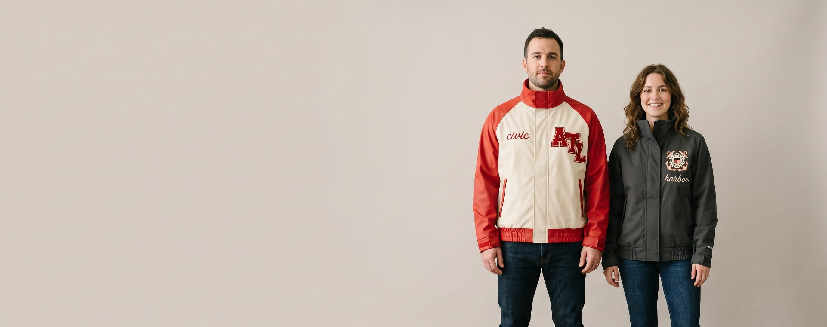 Two lifestyle models in decorated custom rain jackets — one in PU-coated rain jacket with chenille patch + chain-stitch embroidery + one in 3-layer technical storm rain jacket with heritage flat-embroidered emblem