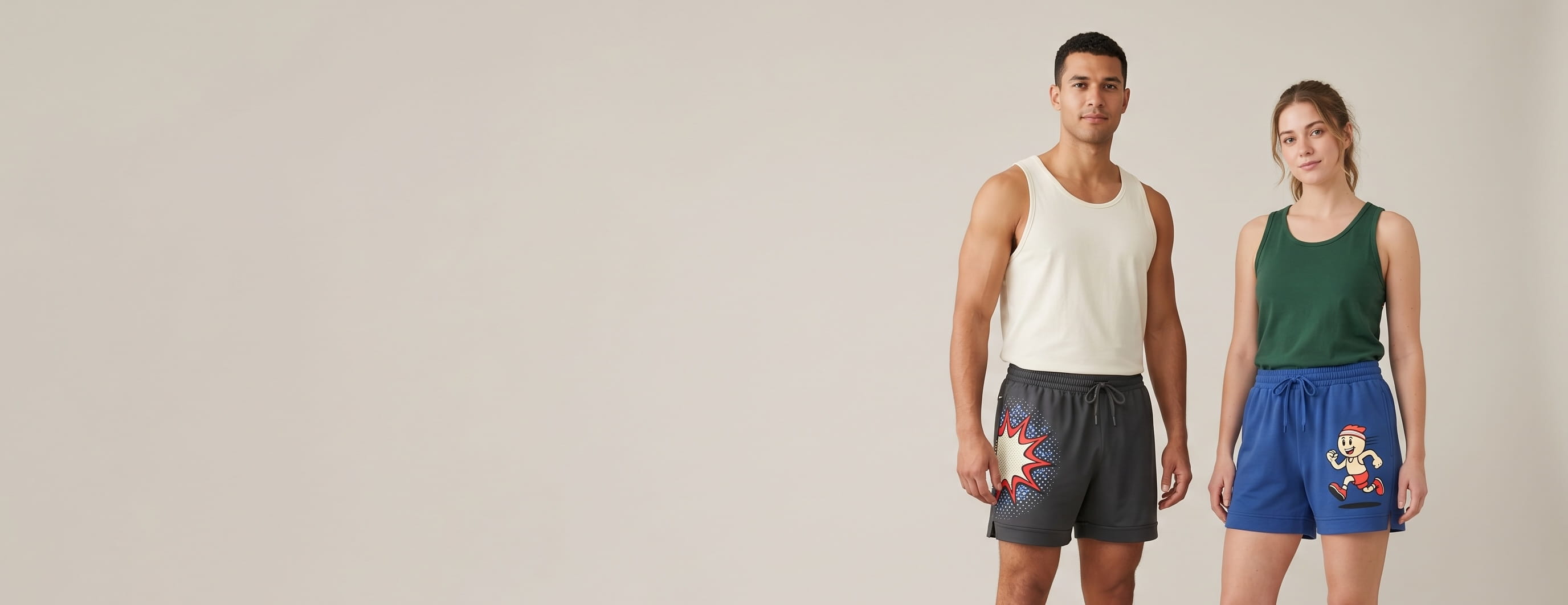 Two lifestyle models in decorated custom running shorts — one in anthracite polyester performance running shorts with a small side-seam emblem + one in cobalt-blue heritage cotton-interlock running shorts with a front-thigh full-color DTG composition