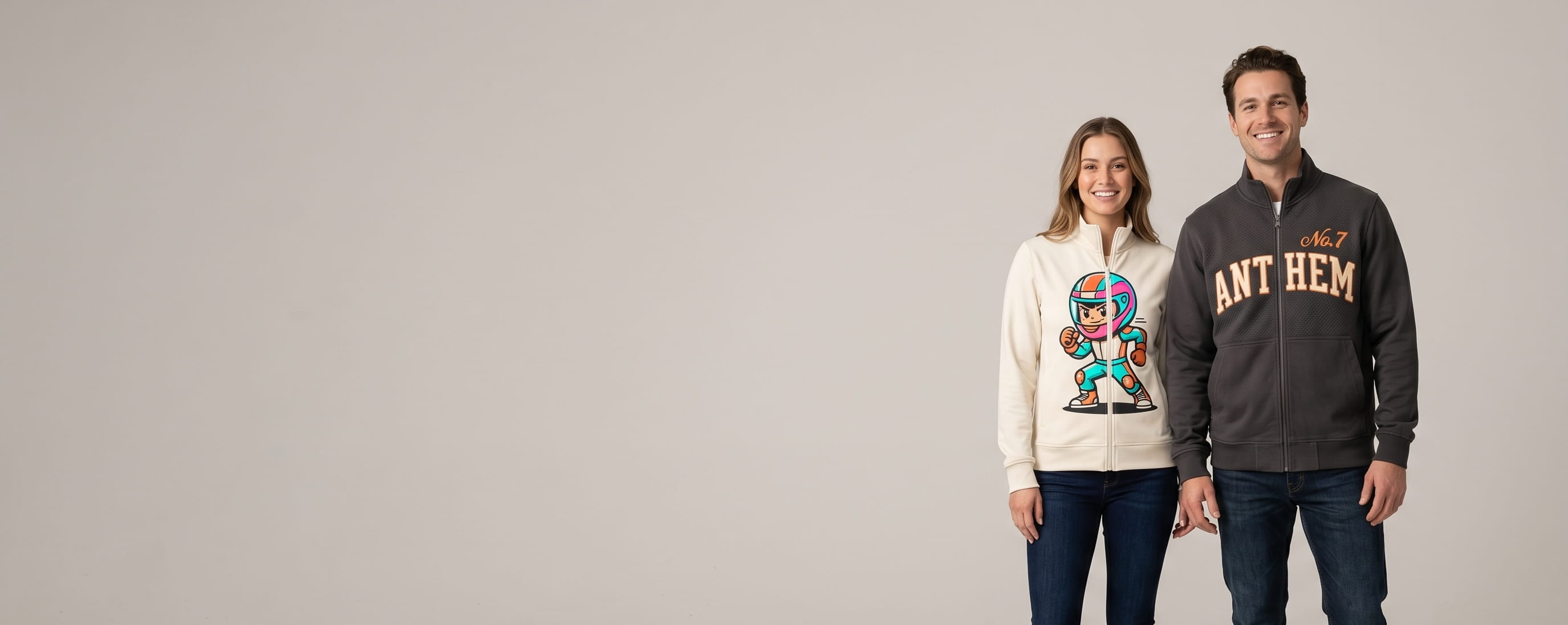 Two lifestyle models in decorated custom zip-up jackets (no hood) — one in anthracite heritage cotton-twill zip-up with flat-embroidered emblem + one in cream performance stretch zip-up with full-color DTG composition