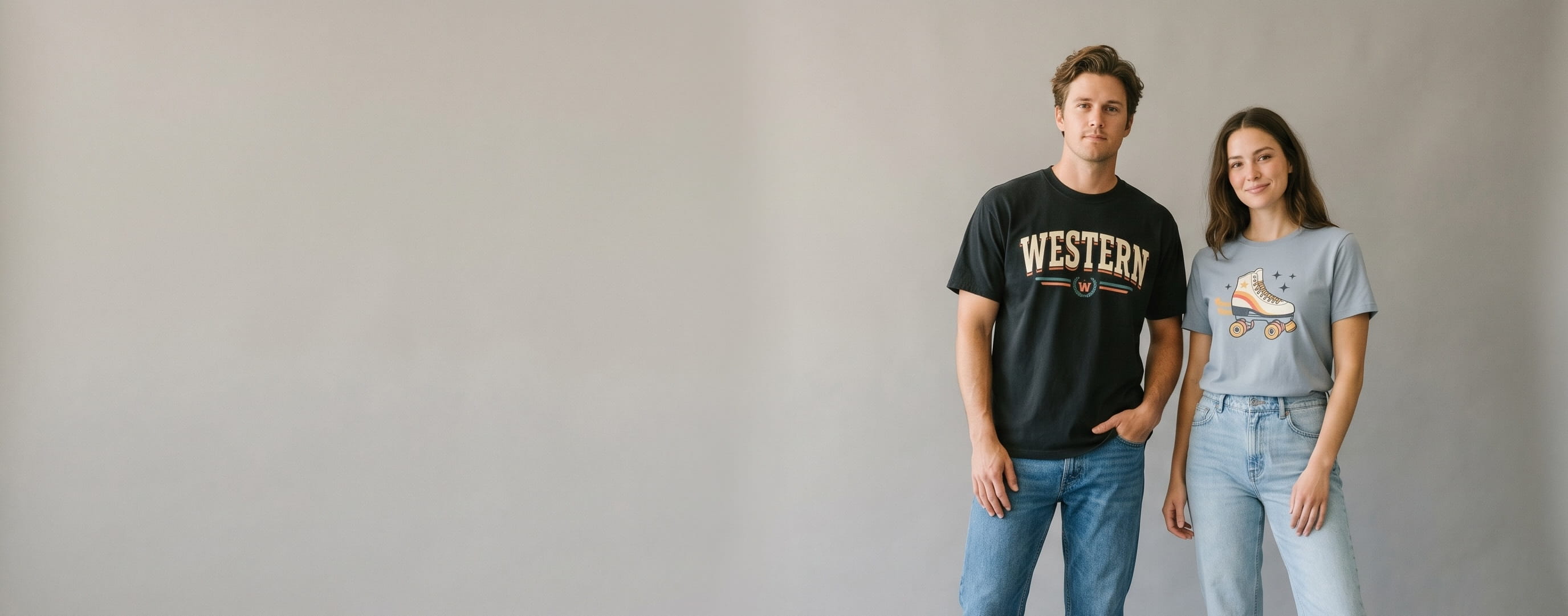 Two everyday-essentials lifestyle models wearing decorated Hanes — retro western slab-serif wordmark plastisol screen print on the man's vintage-black Beefy-T heavyweight cotton tee and a vintage roller-skate emblem full-color DTG on the woman's light-steel ComfortSoft soft ringspun tee