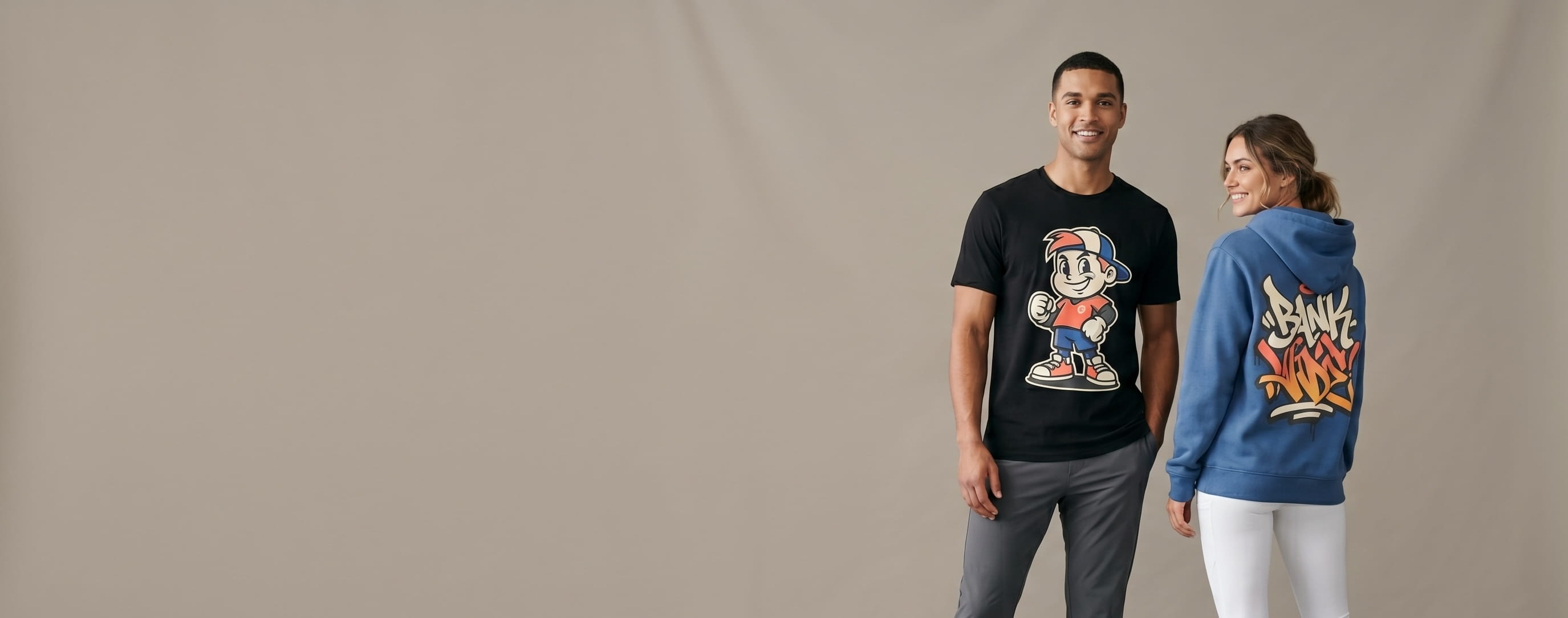 Two athletic-lifestyle models wearing decorated Nike apparel — a full-front cartoon-mascot screen print on the man's black Core Cotton tee and a full-back graffiti-wordmark print on the woman's court-blue club-fleece hoodie