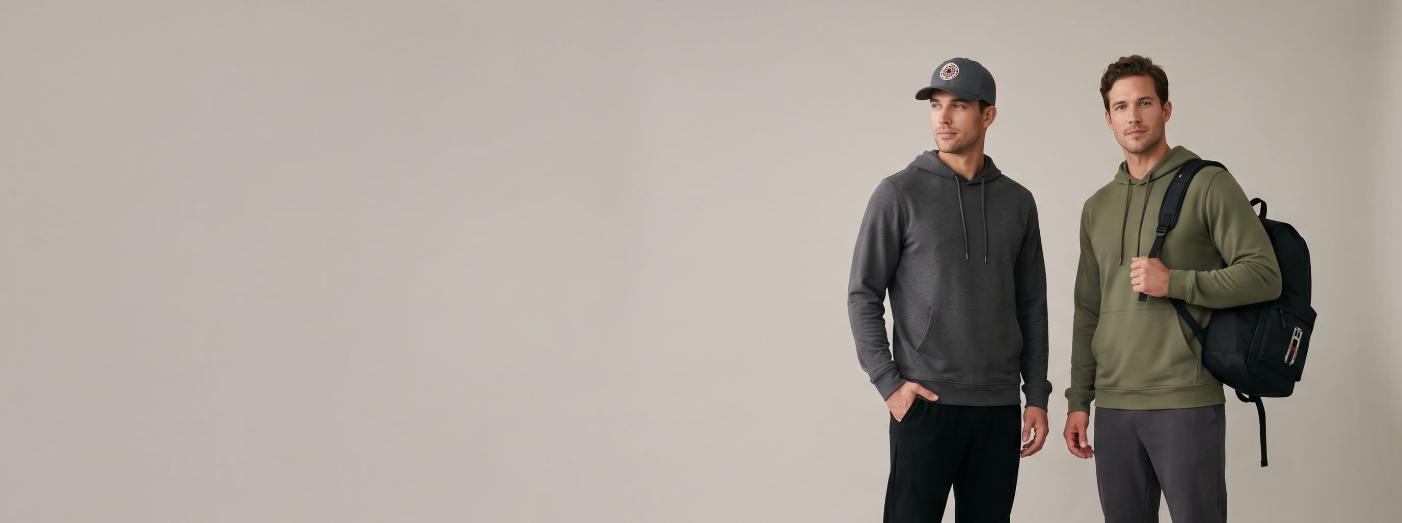 Two sport-tech lifestyle models wearing decorated Oakley — a front-crown brake-rotor 3D puff embroidery on the first model's carbon-grey performance cap and a front-panel suspension-fork screen print on the second model's jet-black sport backpack