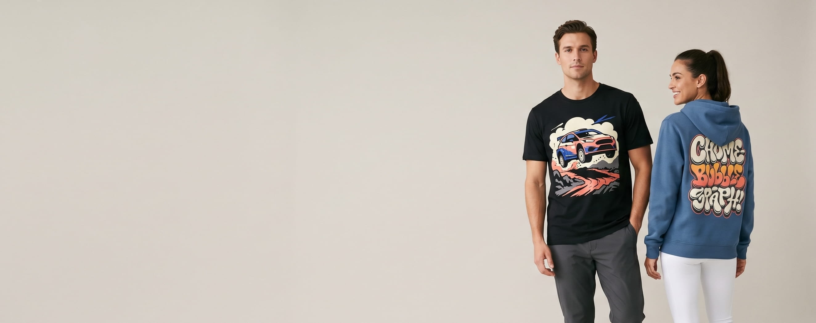 Two athletic-lifestyle models wearing decorated Under Armour apparel — a full-front rally-hatchback screen print on the man's black performance cotton tee and a full-back chrome-bubble graphic on the woman's court-blue brushed-fleece hoodie