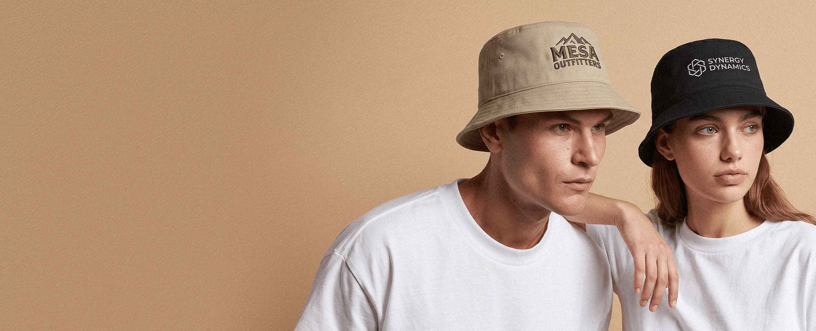 Two models wearing decorated Atlantis Headwear sustainable bucket hats in a clean studio