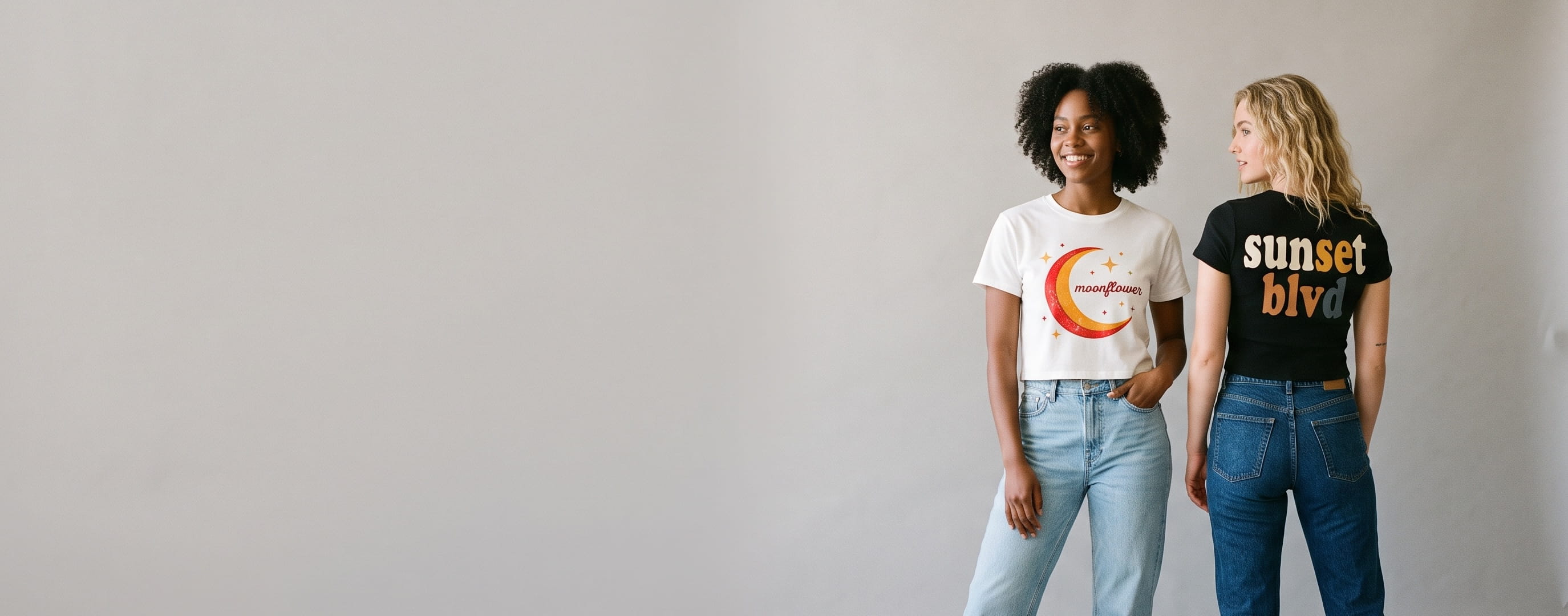 Two lifestyle models in decorated custom crop tees — woman in a white ringspun-cotton crop tee with a full-chest screen print + woman in a black cotton-spandex crop tee with a full-back screen print
