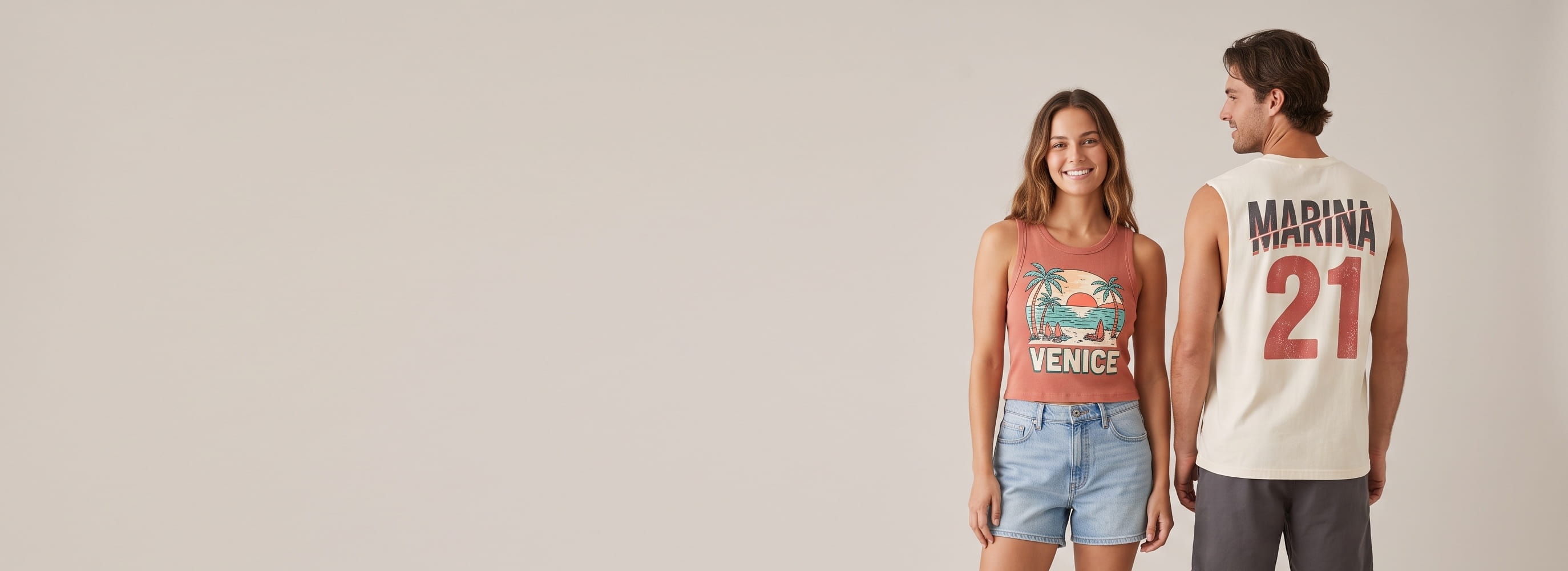 Two lifestyle models in decorated custom tanks — woman in a garment-dyed ribbed crop tank with a full-front screen-printed graphic + man in a heavyweight ring-spun cotton muscle tank with a full-back plastisol graphic