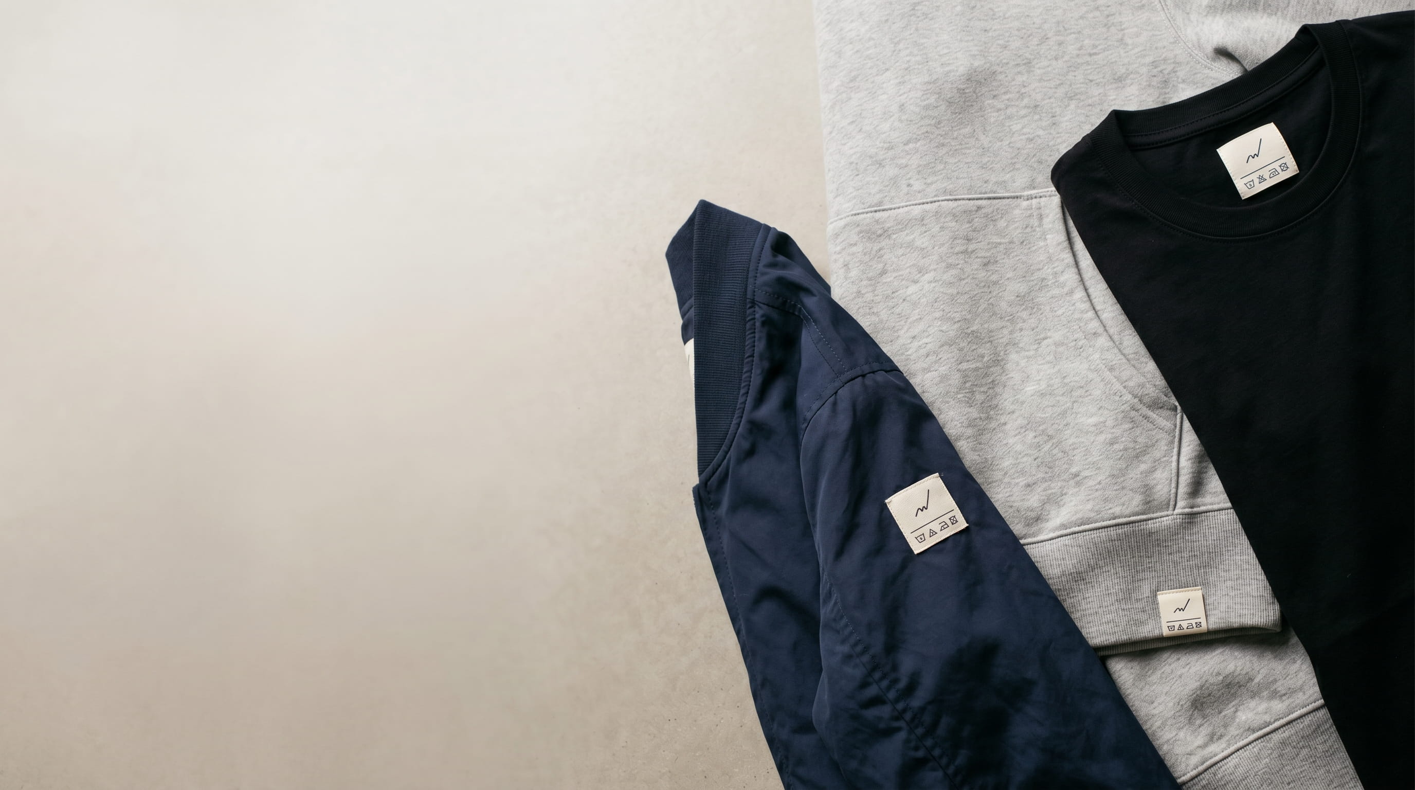 Custom woven brand labels sewn into a tee, hoodie and jacket
