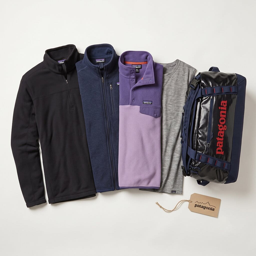 Patagonia 5-piece flat-lay — recycled fleece pullover, full-zip fleece jacket, fleece vest, performance tee, and ripstop duffel bag on a clean studio background