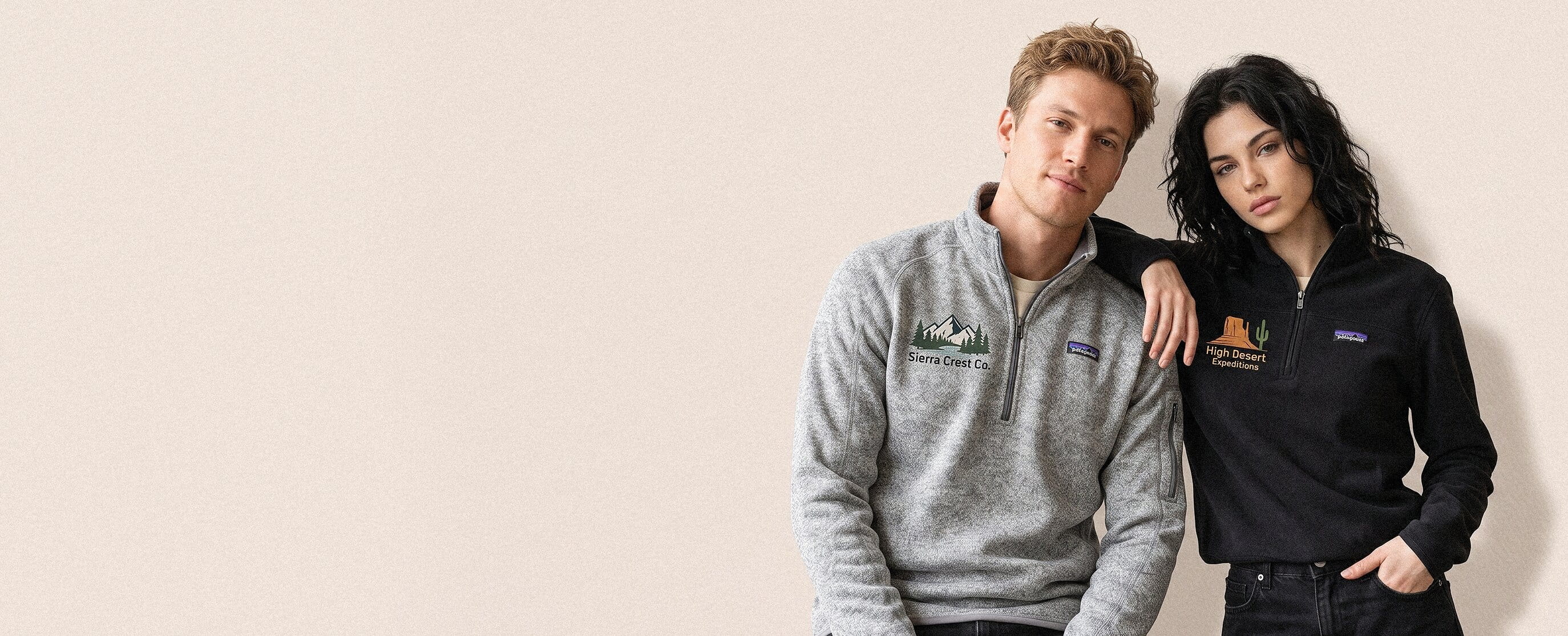 Two outdoor-lifestyle models wearing decorated Patagonia outerwear — a large full-front cartoon-mascot plastisol screen print on the man's forest-green recycled fleece pullover, with the woman turned to show a large full-back graffiti chrome wordmark heat-pressed transfer on her deep-navy fleece quarter-zip