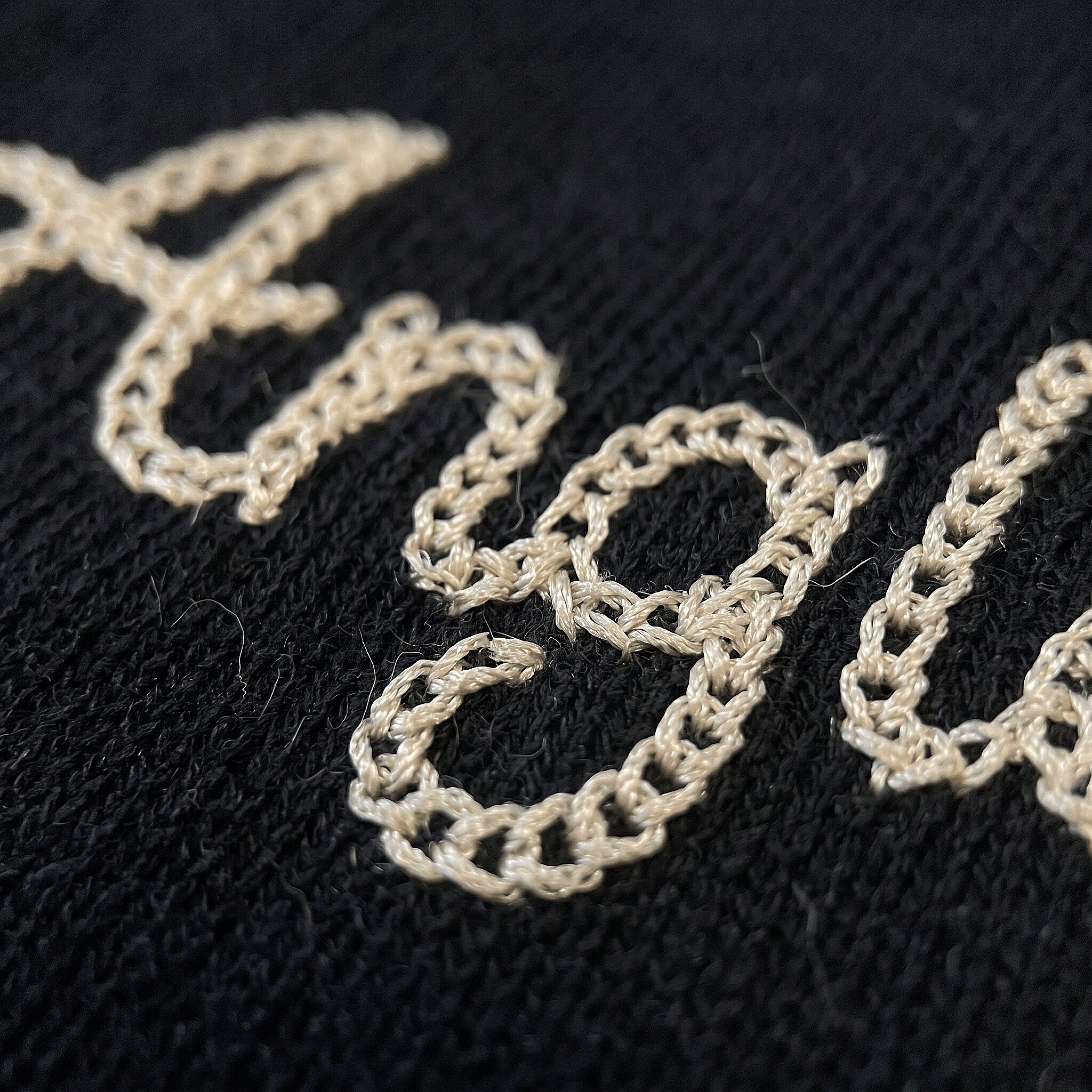 Looped vintage chain stitch script on denim
