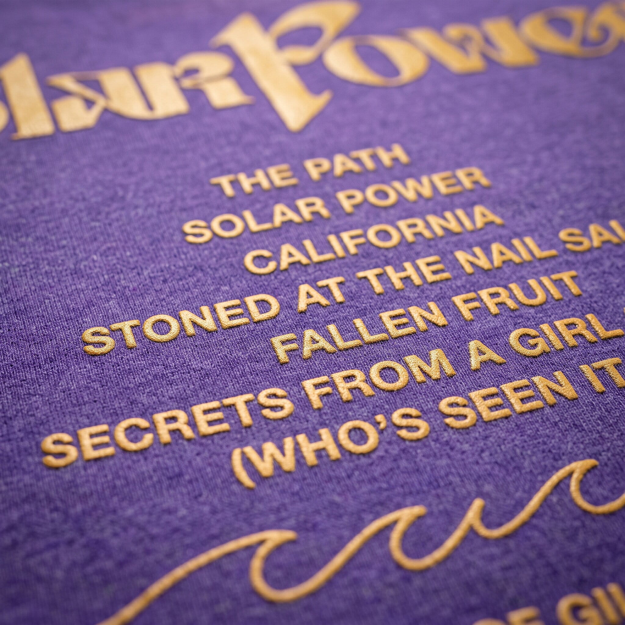 gold plastisol track-list print on a purple shirt