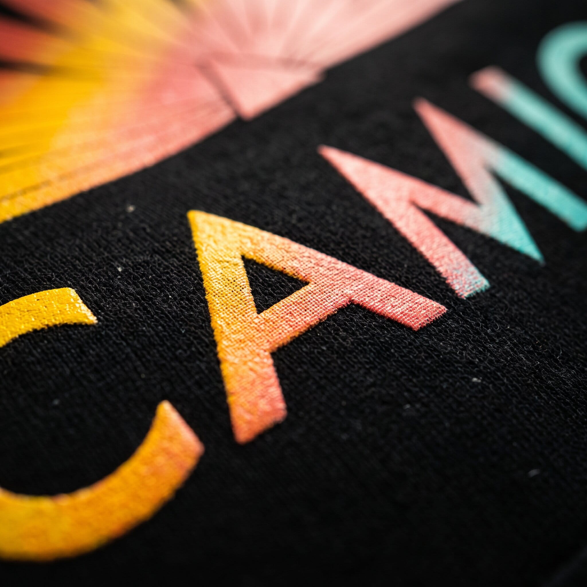 orange-to-teal gradient lettering printed on a black shirt