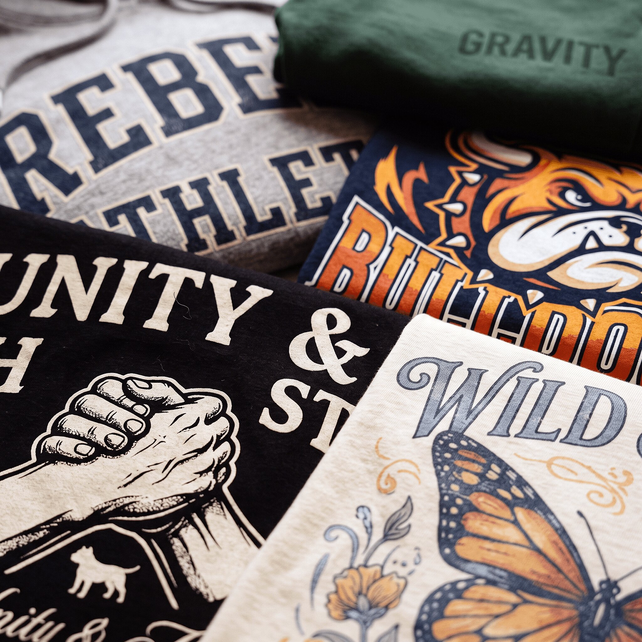 Flat-lay of bold screen-printed tees, hoodies, and sweatpants