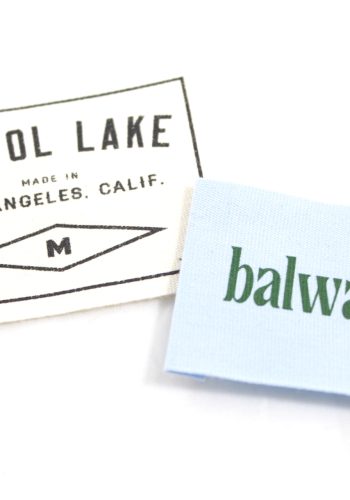 Pistol Lake white woven label next to a blue and green Balware woven label